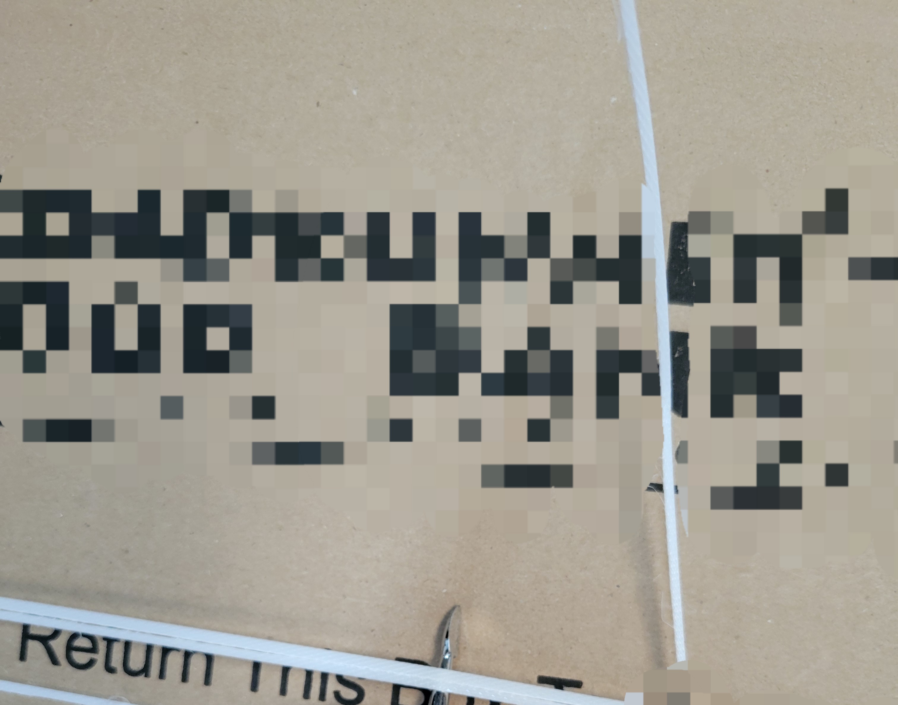 Nail filer tries to open packing straps on cardboard box.